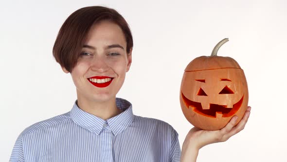 Beautiful Woman Smiling To the Camera, Holding Halloween Carved Pumpkin