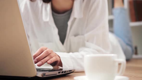 Girl Lying On The Floor Working On A Portable Laptop Pressing Buttons Keys Typing Text Student