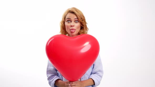 Cheerful Lady Showing Tongue Behind Heart Balloon Sweetheart