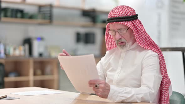 Senior Old Arab Businessman Having Loss on Documents in Caf� 