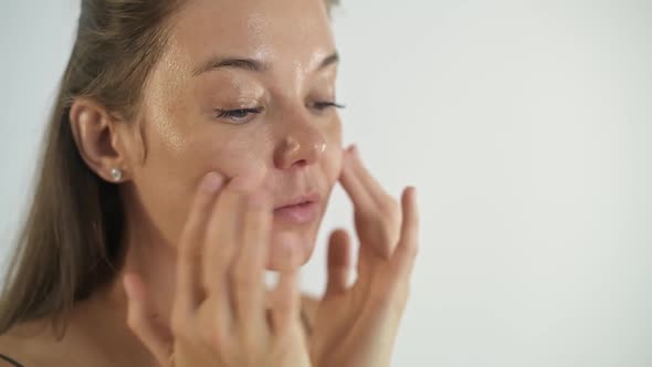 A Young Beautiful Girl Applies Cream to Her Face