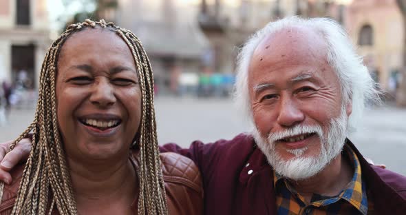 Multiracial senior couple smiling on camera outdoor