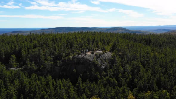 Aerial drone shot pulling back from a group of people hiking and standing together admiring the view