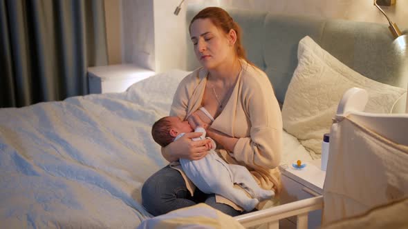 Tired and Exhausted Mother Falling Asleep While Feeding Her Newborn Baby Son with Breast Milk on Bed