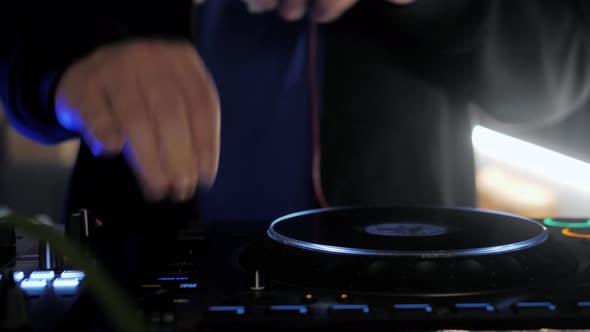 Close Up Dj Hands Disc Jockey Mixing Music on His Deck with His Hands Poised Over the Vinyl Record