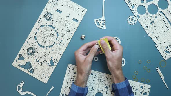 Man using sandpaper for wooden small pieces of puzzle toy.