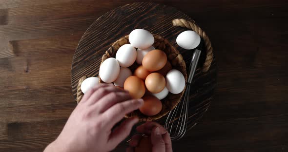 Men's Hands Take Raw Eggs From a Basket. 