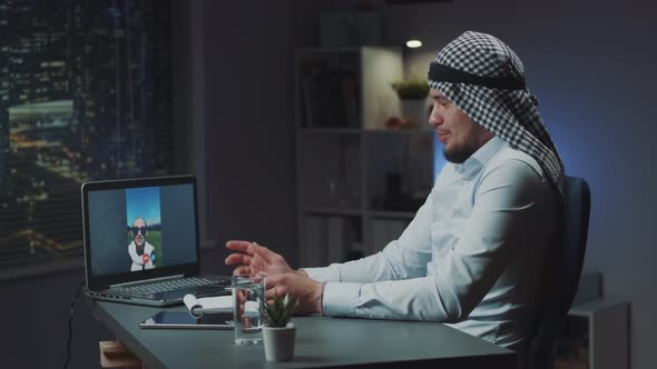 Arabic Man Speaking with Caucasian Woman on Zoom From His Office in the Evening