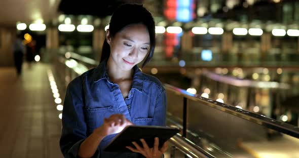 Woman looking at tablet computer at night