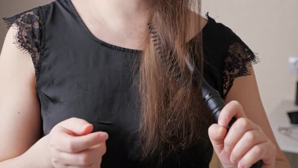 Young Woman Runs Comb Along Dark Brown Hair and Shows Brush