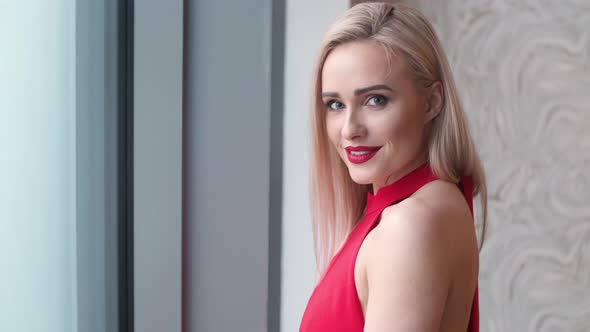 Stylish Elegant Blonde Woman in Home Living Room, Wearing Red Sexy Dress