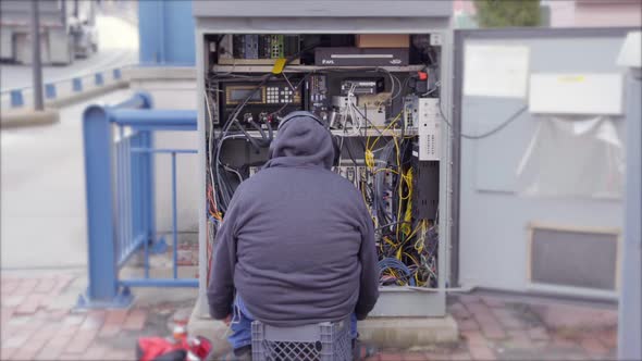 Repairman Sitting In Front Of An Open Electrical Panel Box On The Sidewalk In Boston, Massachusetts,