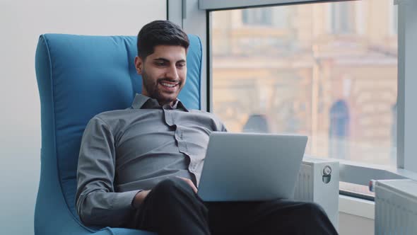 Happy Millennial Indian Corporate Employee in Creative Profession Sits in Comfortable Armchair in