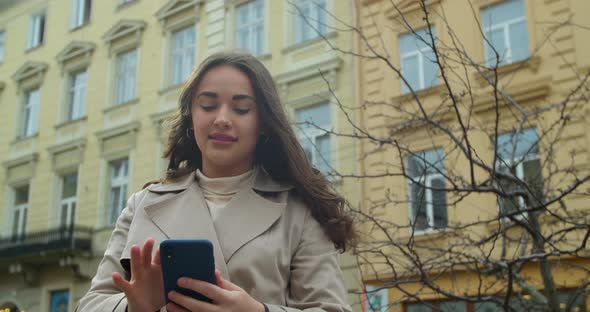 Attractive Young Woman Using Phone in the City Center. Chatting with Friends, Girl Using Cellphone