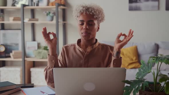 African American Woman Near Laptop Practicing Meditation at Home Office Desk