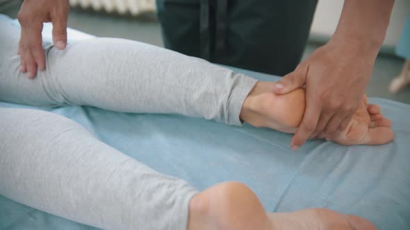 Woman Having an Osteopath Treatment - the Doctor Pushing on Her Feet and Knee