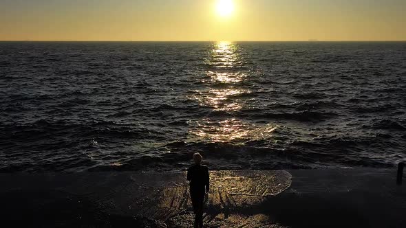 Slow motion female walking by the ocean with waves on sunset