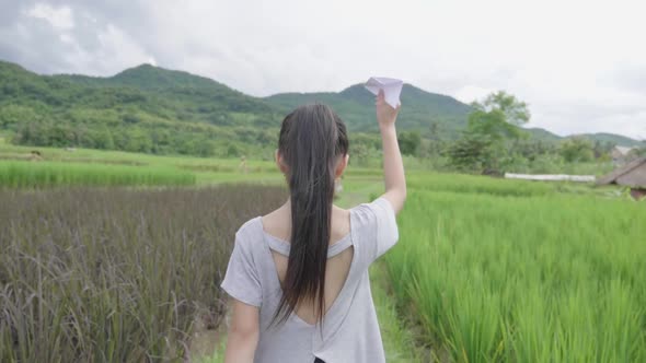 Girl Walking With A Paper Airplane In Rice Field
