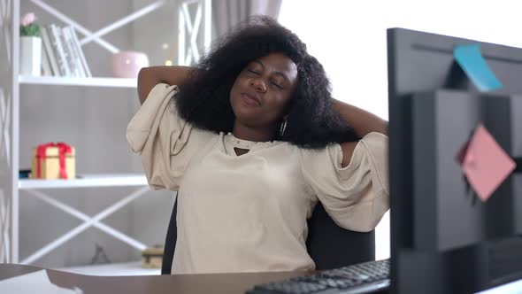 Relaxed Confident African American Freelancer Sitting on Chair at Computer Desk Opening Eyes Looking