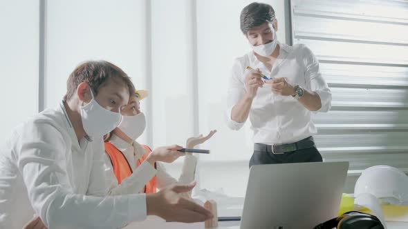 engineer caucasian male and asian female serious concentrate meeting with mask protection