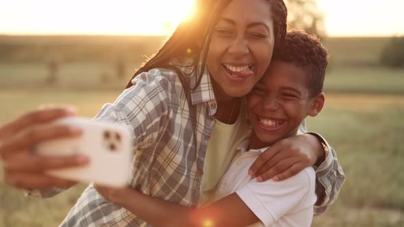 A cheerful afro-american mother is taking selfie photo with her son