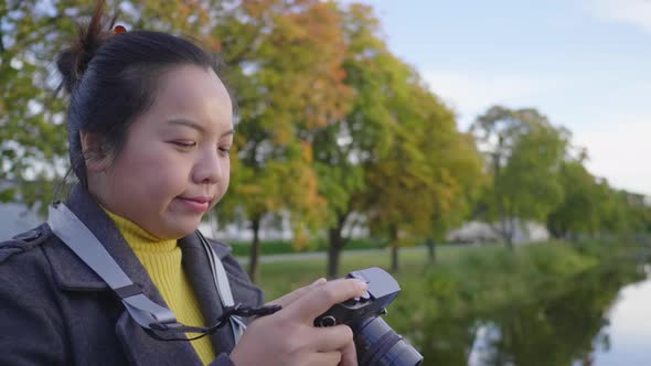 Asian woman standing and taking a picture by camera outside