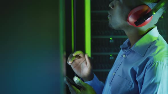 African american male computer technician using tablet working in business server room