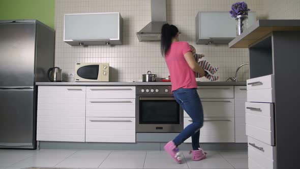 Woman Playing and Dancing with Baby Son in Kitchen