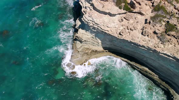 Strong Waves Break on Rocky Seashore on Sunny Day