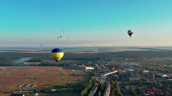 Multicolored balloons fly over trees. Nice top view of the park, forest covered with greenery.