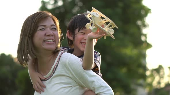 Cute Asian Mother And Son Playing Wooden Airplane Together In The Park Outdoors 