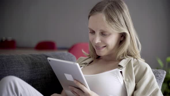 Smiling Beautiful Young Woman Using Tablet at Home