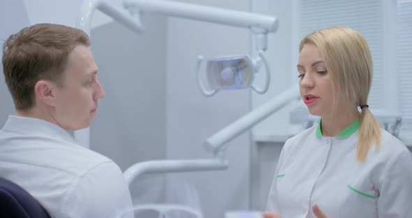 Beautiful Woman Dentist Consults a Patient in a Modern Office of a Dental Clinic