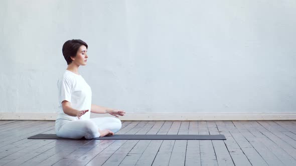 Young and fit woman practicing yoga indoor in the class.