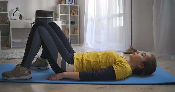 Morning Workout at Home Teen Girl Is Training Alone in Living Room Lying on Floor and Lifting Hips