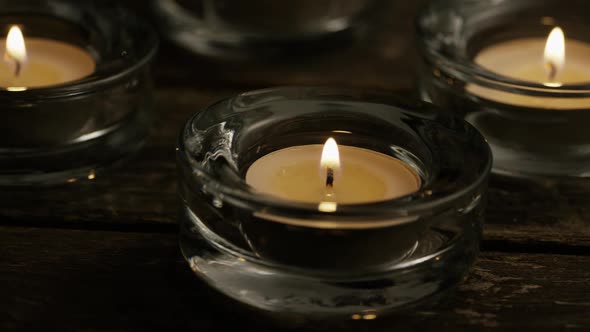 Tea candles with flaming wicks on a wooden background 