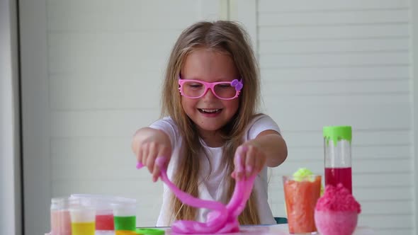 Little girl stretching pink slime to the sides.