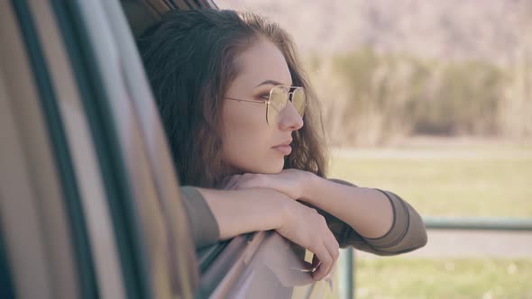 Woman in Stylish Yellow Glasses Leans Out of Open Car Window