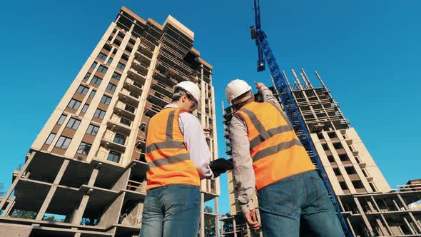 Backside View of Two Engineers at High-rise Buildings in Progress