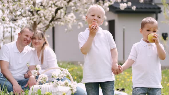 Two Brothers Holding Hands Standing and Eating Apples