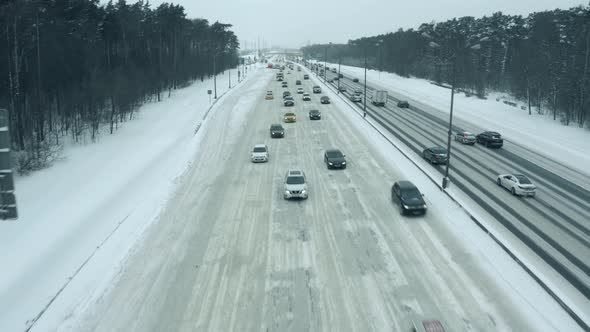 Cars Driving Along the Snow Covered Highway in Winter