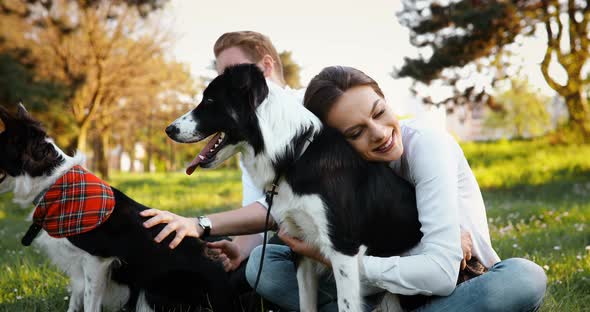 Beautiful Couple Cuddling and Walking Dogs Outdoors