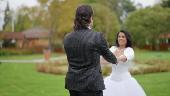 the Bride and Groom Hold Hands Laugh and Spin in the Park