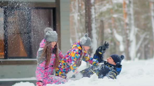 Happy Girl with Mother and Father Plays with Snow in Forest
