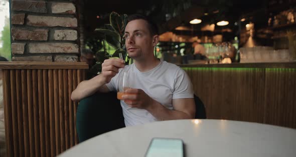 Man Drinks Fruity Juice in Restaurant