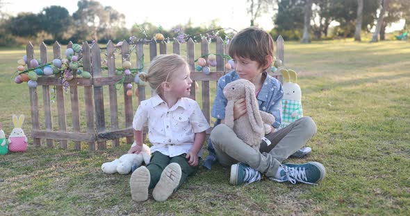 Two boys dressed in Easter attire play with a stuffed Easter Bunny and give each other a hug.