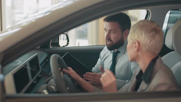 Blond Business Woman Sitting Inside Modern Auto Looking at Dashboards Design