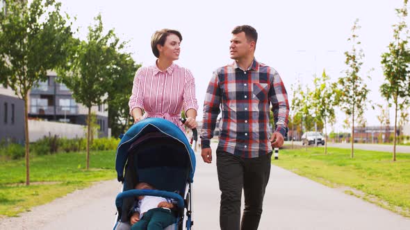 Family with Baby in Stroller Walking Along City