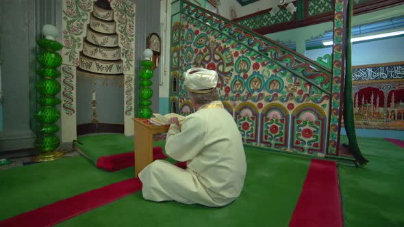 Muslim Mosque Teacher is reading the Quran in Small Historic Wooden Masjid