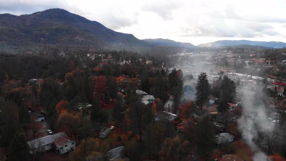 Aerial view of smoke over rural mountain neighborhood during winter season.